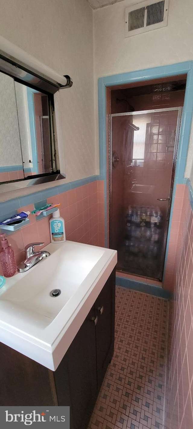 bathroom with tile walls, walk in shower, backsplash, and vanity