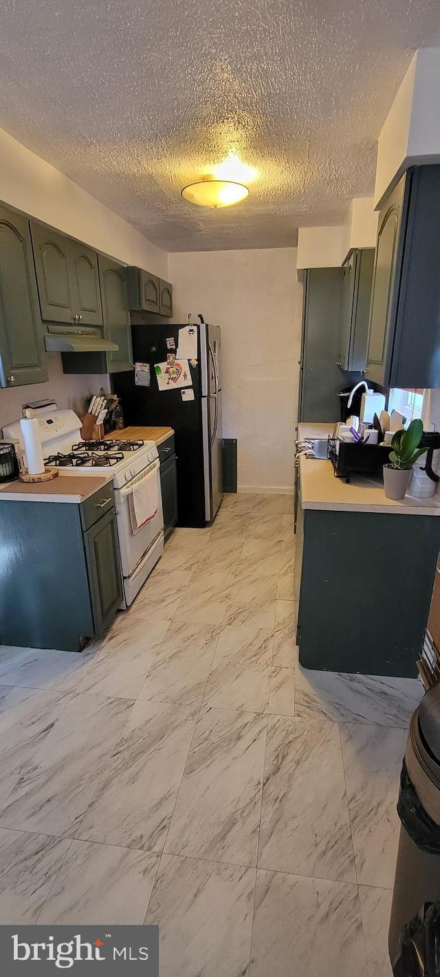 kitchen with gas range gas stove, stainless steel refrigerator, and a textured ceiling