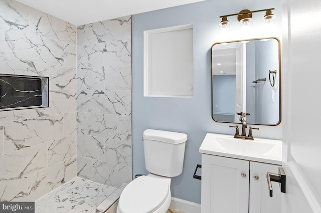 bathroom featuring tiled shower, vanity, and toilet