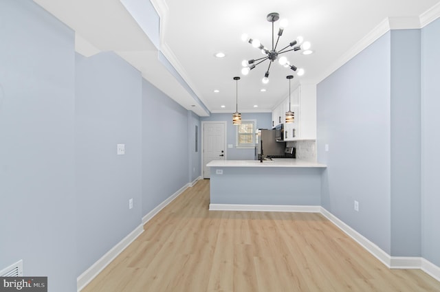 kitchen featuring hanging light fixtures, kitchen peninsula, white cabinetry, and light hardwood / wood-style flooring