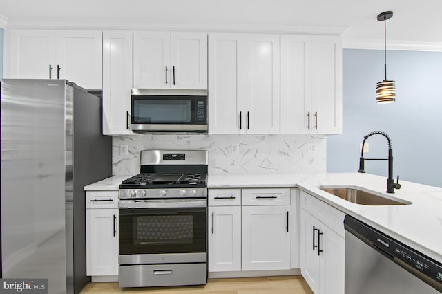 kitchen featuring light stone counters, white cabinets, pendant lighting, stainless steel appliances, and sink