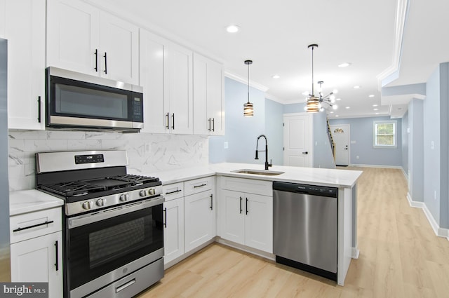 kitchen featuring hanging light fixtures, sink, kitchen peninsula, white cabinetry, and stainless steel appliances