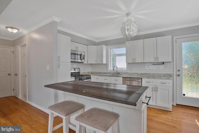 kitchen featuring stainless steel appliances, light hardwood / wood-style floors, and white cabinetry