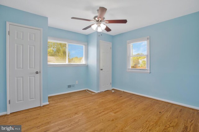 unfurnished bedroom featuring multiple windows, light hardwood / wood-style flooring, and ceiling fan