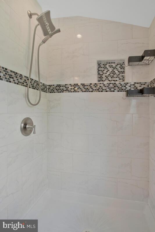 bathroom featuring lofted ceiling and a tile shower