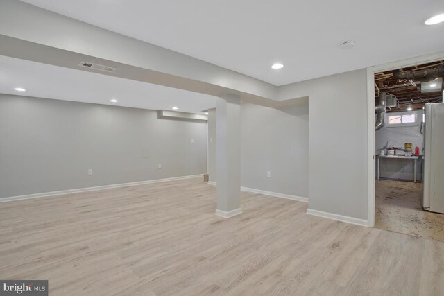 basement with white refrigerator and light wood-type flooring