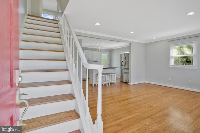 staircase featuring hardwood / wood-style flooring, plenty of natural light, and ornamental molding