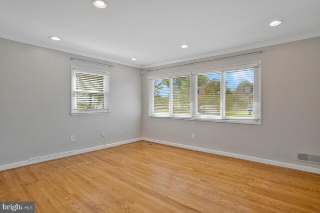 empty room with crown molding, a healthy amount of sunlight, and light hardwood / wood-style floors