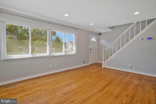 foyer entrance with light hardwood / wood-style floors and crown molding