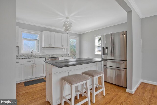 kitchen featuring light wood-type flooring, appliances with stainless steel finishes, a kitchen island, and white cabinets