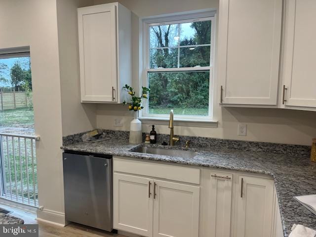 kitchen with stone countertops, light hardwood / wood-style flooring, sink, stainless steel dishwasher, and white cabinets