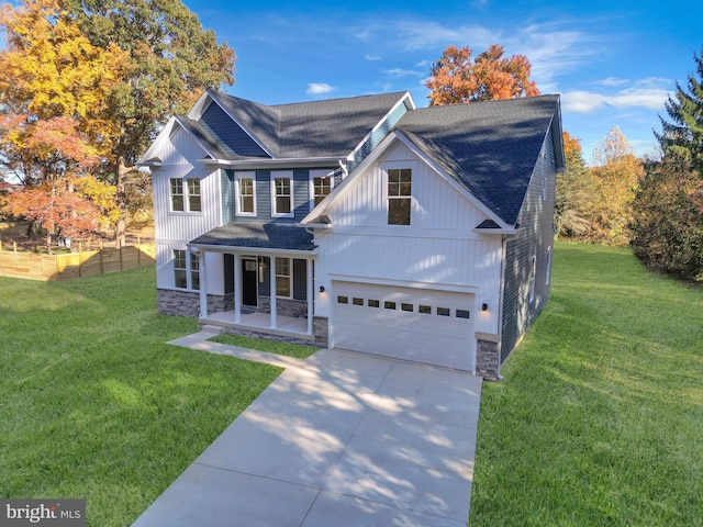 view of front of home with a porch, an attached garage, stone siding, and a front yard