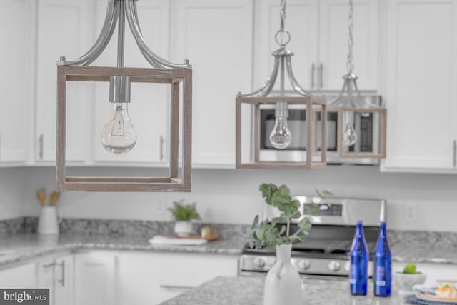 kitchen with light stone countertops, electric range, and white cabinetry