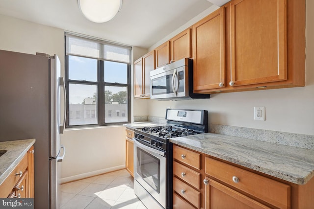 kitchen featuring light stone counters, stainless steel appliances, and light tile patterned floors