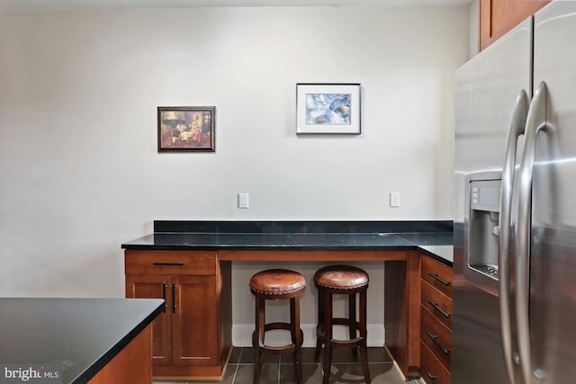 kitchen with dark tile patterned floors and stainless steel refrigerator with ice dispenser