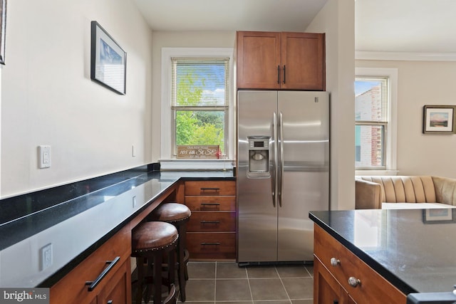 kitchen featuring dark tile patterned flooring, a breakfast bar area, and stainless steel fridge with ice dispenser