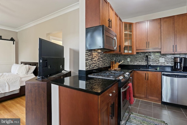 kitchen featuring crown molding, a barn door, stainless steel appliances, dark hardwood / wood-style flooring, and sink