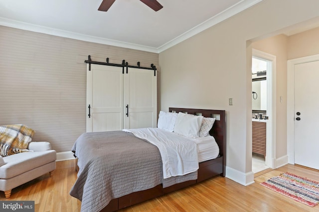 bedroom featuring ornamental molding, light hardwood / wood-style flooring, ceiling fan, and a barn door