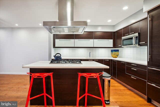 kitchen featuring a kitchen bar, a center island, and island exhaust hood