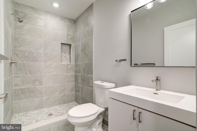 bathroom featuring vanity, toilet, and tiled shower