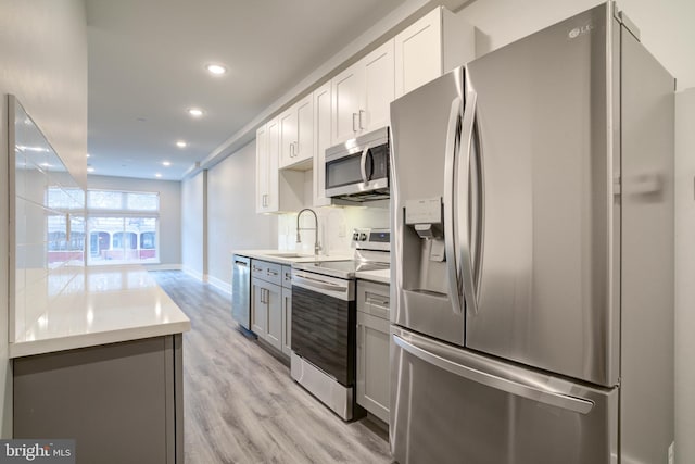 kitchen with white cabinets, sink, stainless steel appliances, and light hardwood / wood-style floors