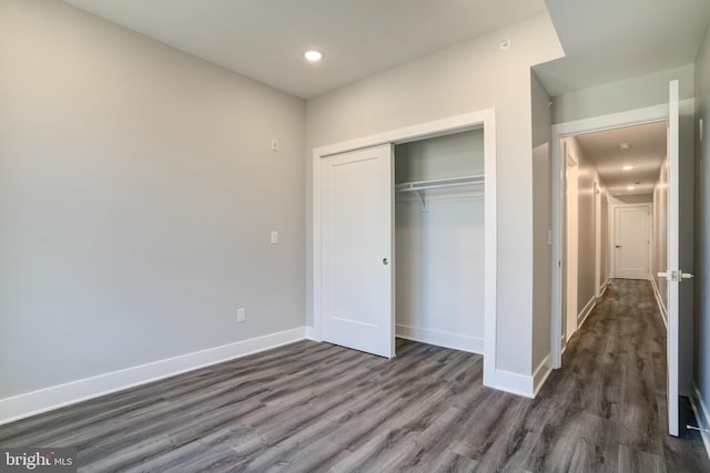 unfurnished bedroom with a closet and dark hardwood / wood-style floors