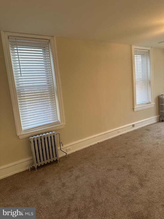 empty room featuring carpet and radiator heating unit