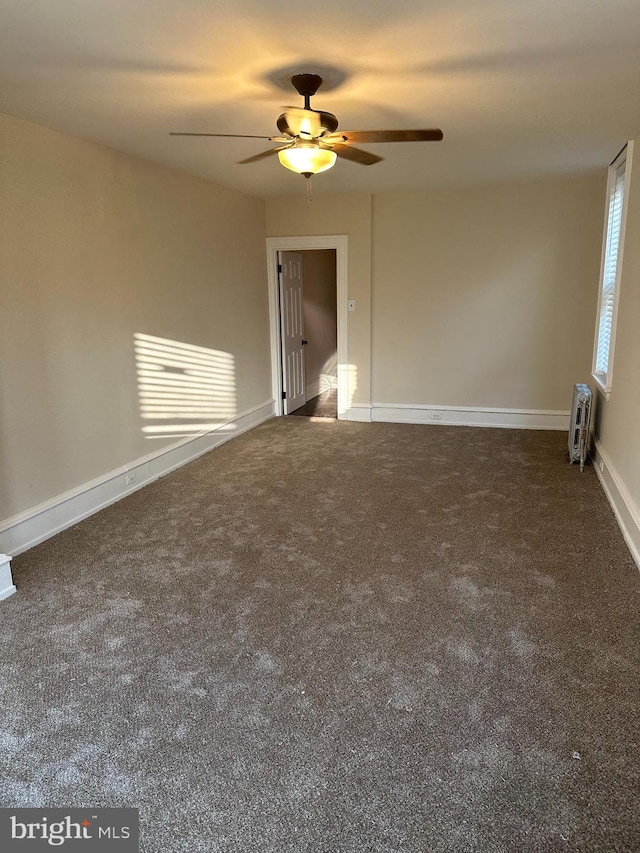 spare room featuring dark carpet and ceiling fan