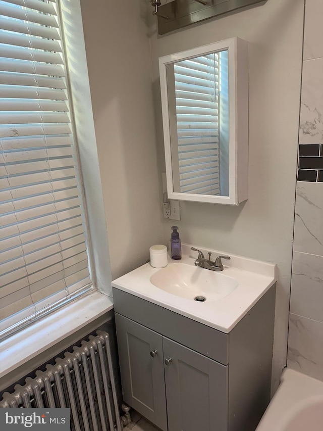 bathroom with radiator heating unit, vanity, and a bathing tub