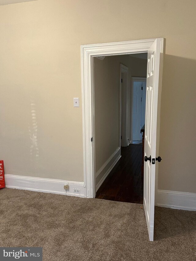 hallway featuring dark colored carpet