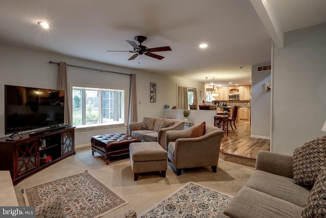 living room with light wood-type flooring and ceiling fan with notable chandelier