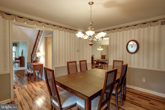 dining space with crown molding, wood-type flooring, and an inviting chandelier