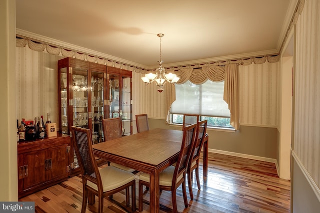 dining room with crown molding, hardwood / wood-style flooring, and an inviting chandelier