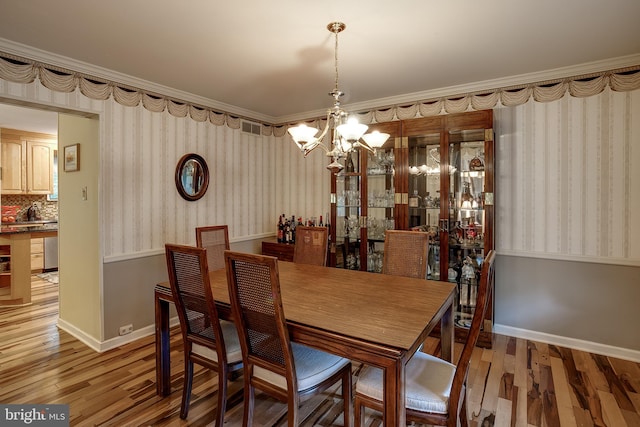 dining area featuring crown molding, a notable chandelier, and wood-type flooring