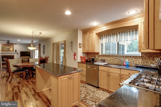 kitchen with a kitchen island, stainless steel dishwasher, sink, light brown cabinetry, and light hardwood / wood-style floors