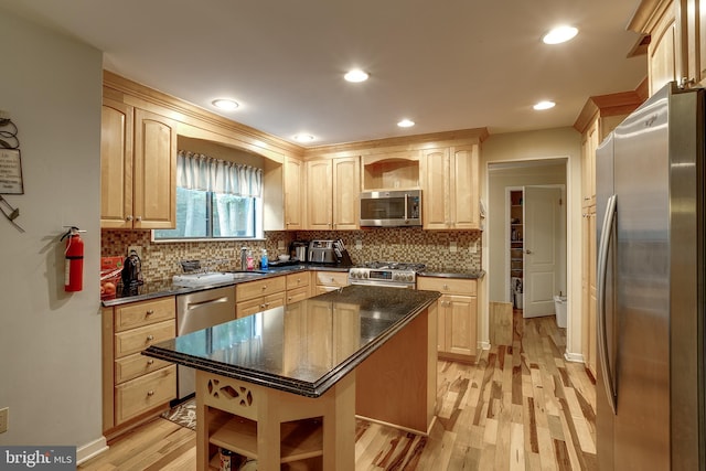 kitchen with backsplash, light brown cabinetry, light wood-type flooring, stainless steel appliances, and a center island