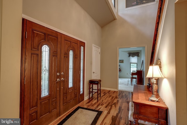 foyer entrance featuring a towering ceiling and light hardwood / wood-style flooring