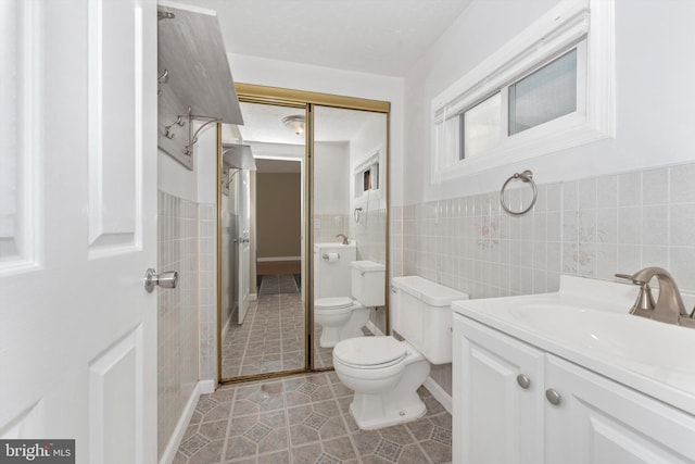 bathroom featuring tile walls, vanity, walk in shower, tile patterned flooring, and toilet