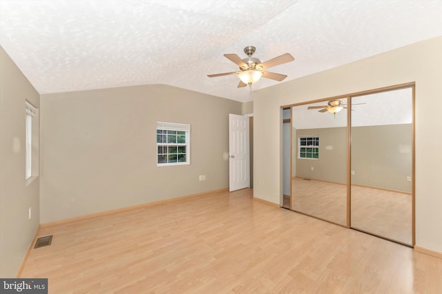 unfurnished bedroom with ceiling fan, a textured ceiling, a closet, and light hardwood / wood-style floors