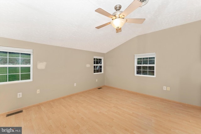 spare room featuring light wood-type flooring, lofted ceiling, ceiling fan, and a textured ceiling