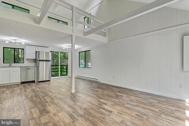 unfurnished living room with wooden walls, light hardwood / wood-style floors, high vaulted ceiling, and a baseboard heating unit