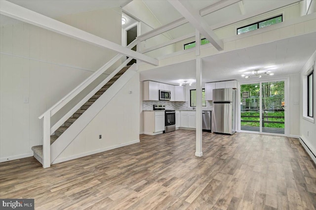 unfurnished living room with hardwood / wood-style floors and high vaulted ceiling