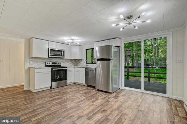 kitchen with sink, stainless steel appliances, backsplash, white cabinets, and hardwood / wood-style flooring