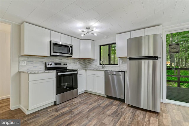 kitchen with a healthy amount of sunlight, white cabinetry, dark wood-type flooring, and stainless steel appliances