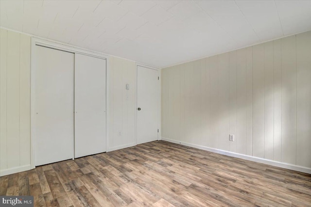 unfurnished bedroom with wood walls and wood-type flooring