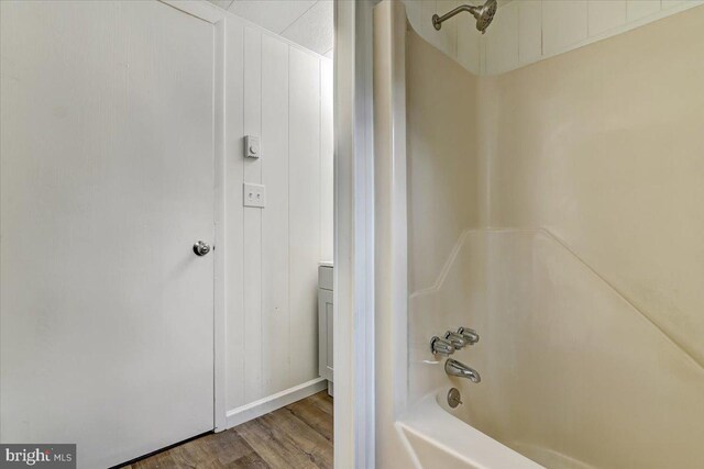 bathroom with hardwood / wood-style flooring and washtub / shower combination