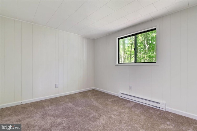 carpeted spare room with a baseboard heating unit