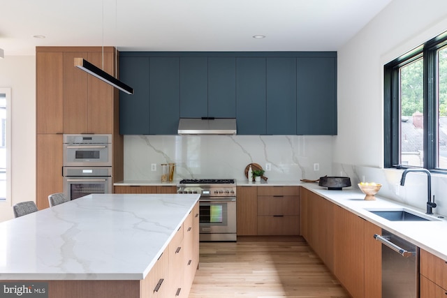 kitchen featuring a kitchen island, light hardwood / wood-style flooring, stainless steel appliances, sink, and light stone counters