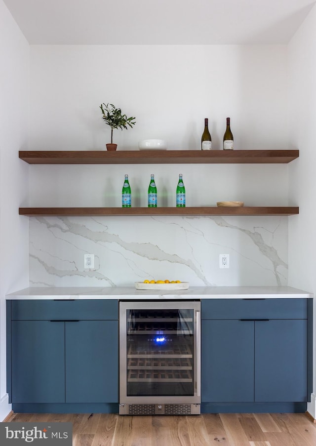 bar with light hardwood / wood-style floors, wine cooler, and blue cabinetry