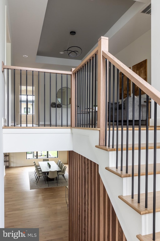 stairs featuring a raised ceiling and wood-type flooring